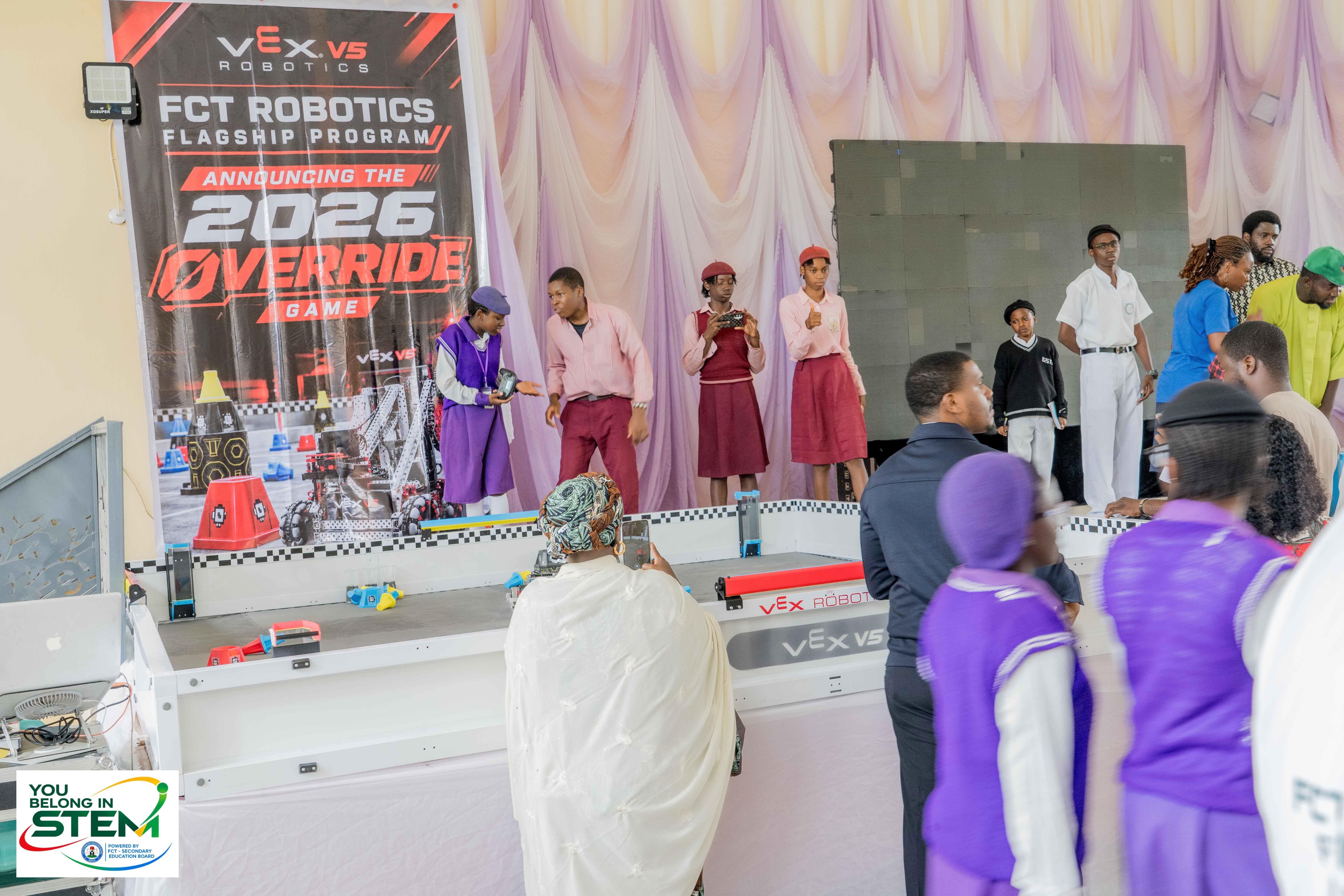 Students and guests around a VEX V5 Robotics demonstration field